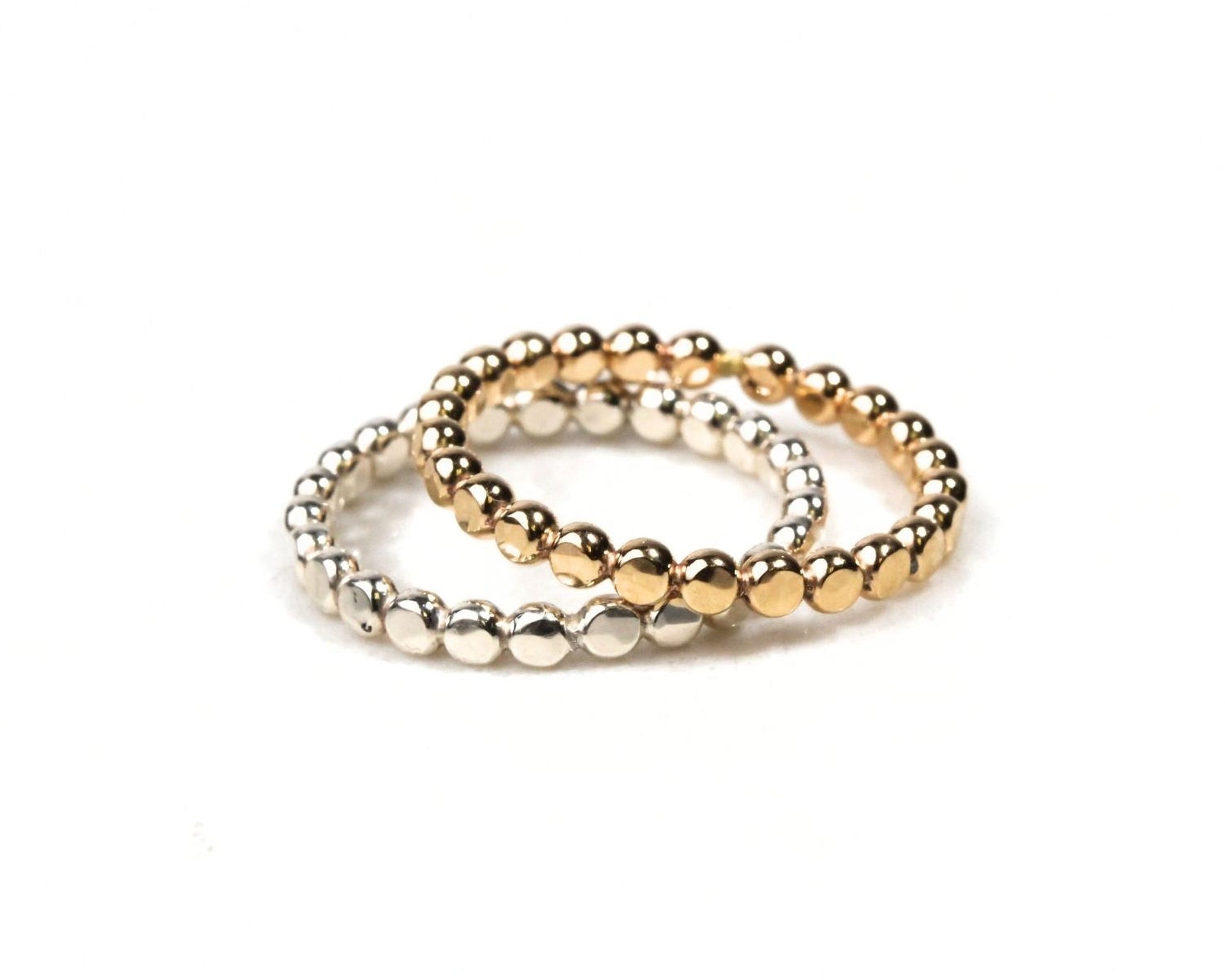 Two rings with a row of small, shiny, metallic beads in gold and silver colors.