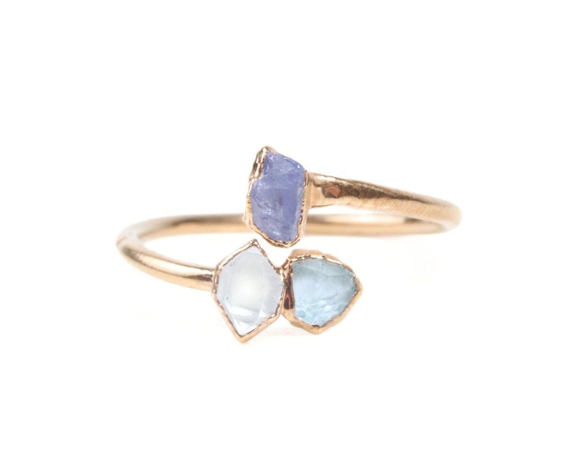 A gold ring with two gemstones, one blue and one clear, set in a gold band.