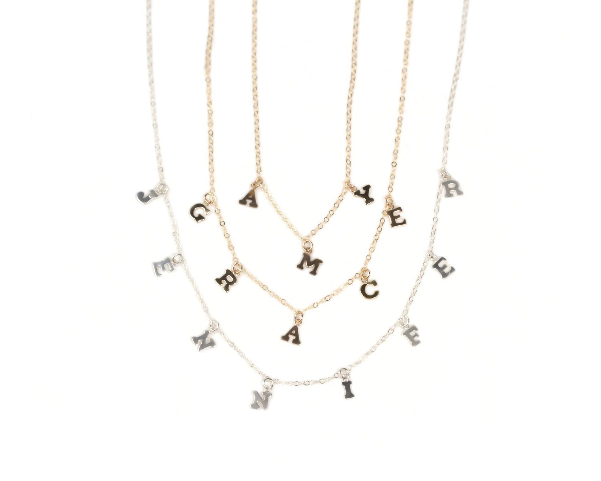 a collection of necklaces with individual letter charms attached to them.