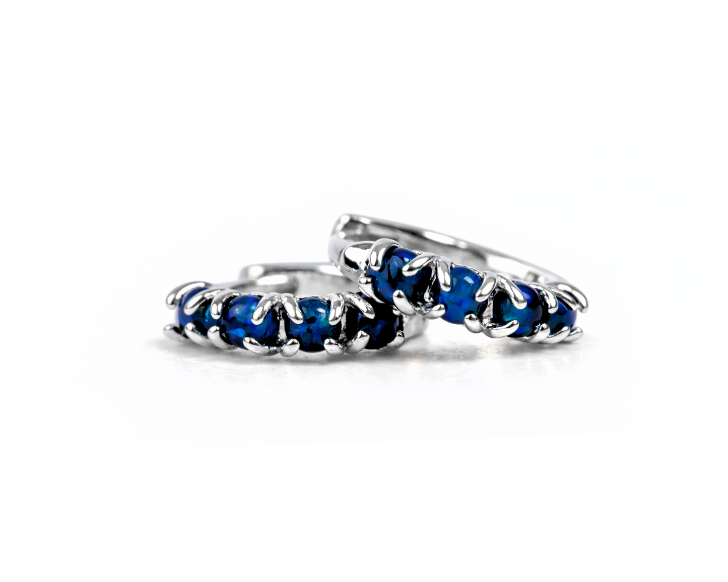 A pair of silver earrings with blue gemstones, arranged in a row.
