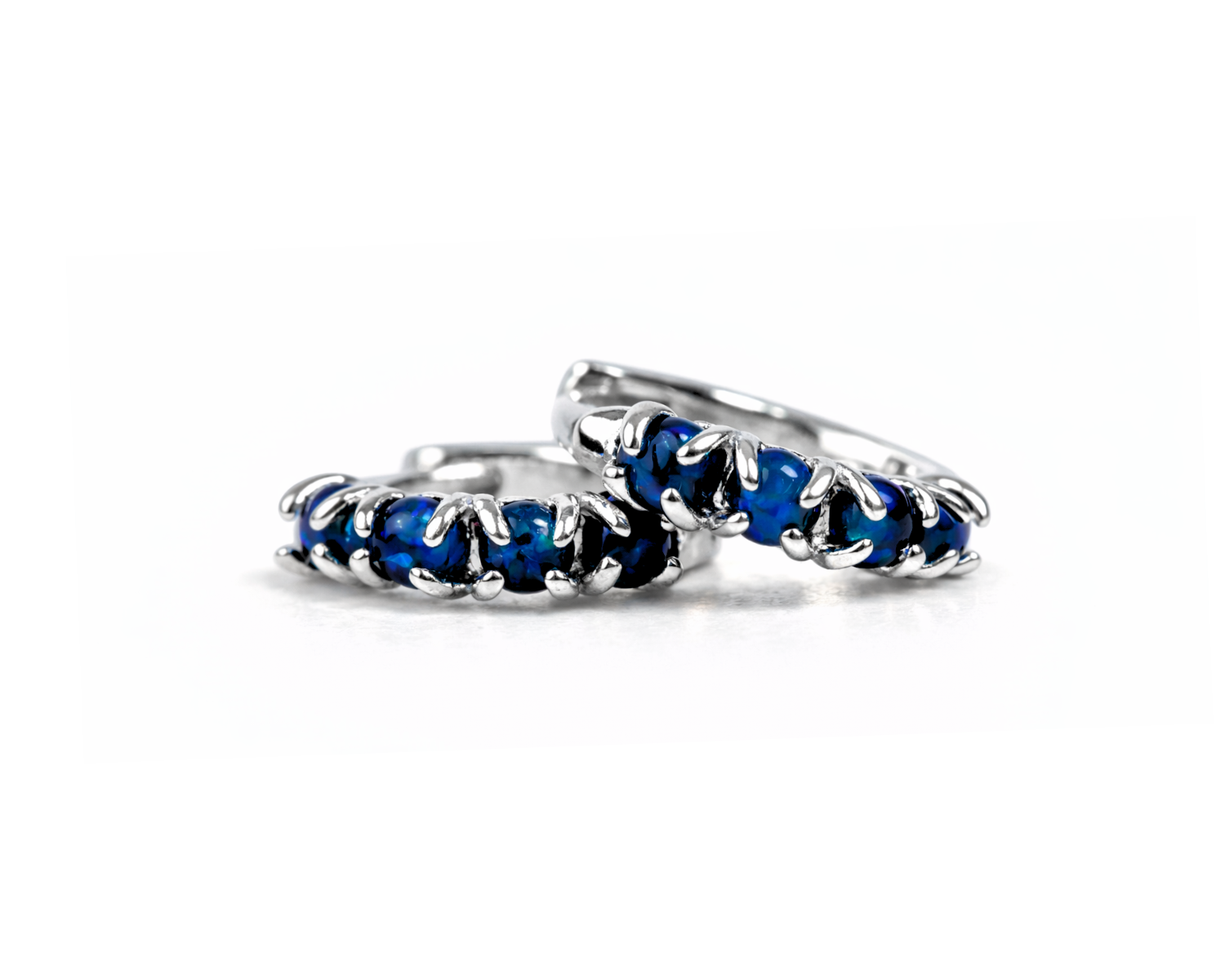 A pair of silver earrings with blue gemstones, arranged in a row.