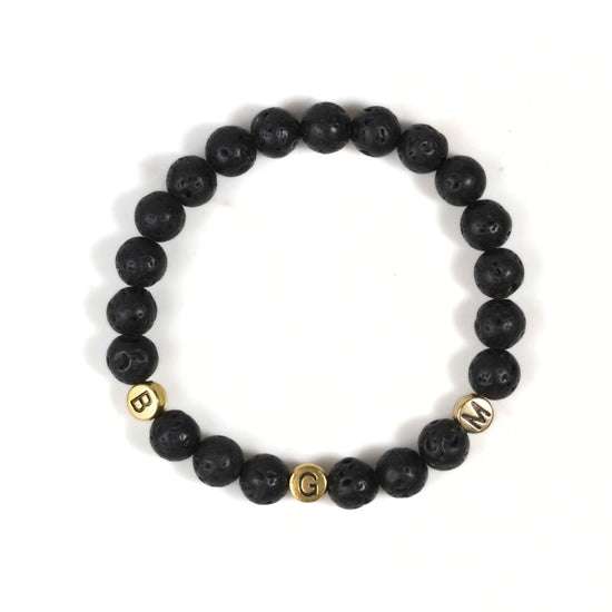 A bracelet made of black beads with gold letters spelling out the word "BGM".