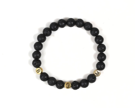 A bracelet made of black beads with gold letters spelling out the word "BGM".