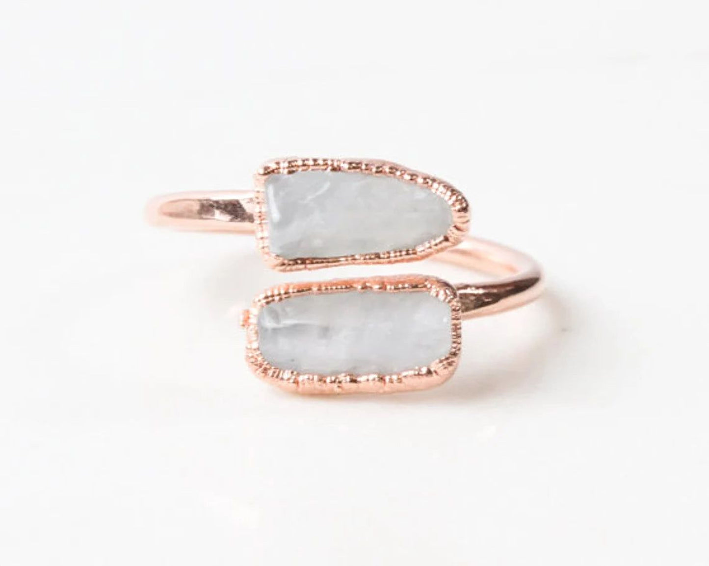 A ring with two large, white stones set in a rose gold band.