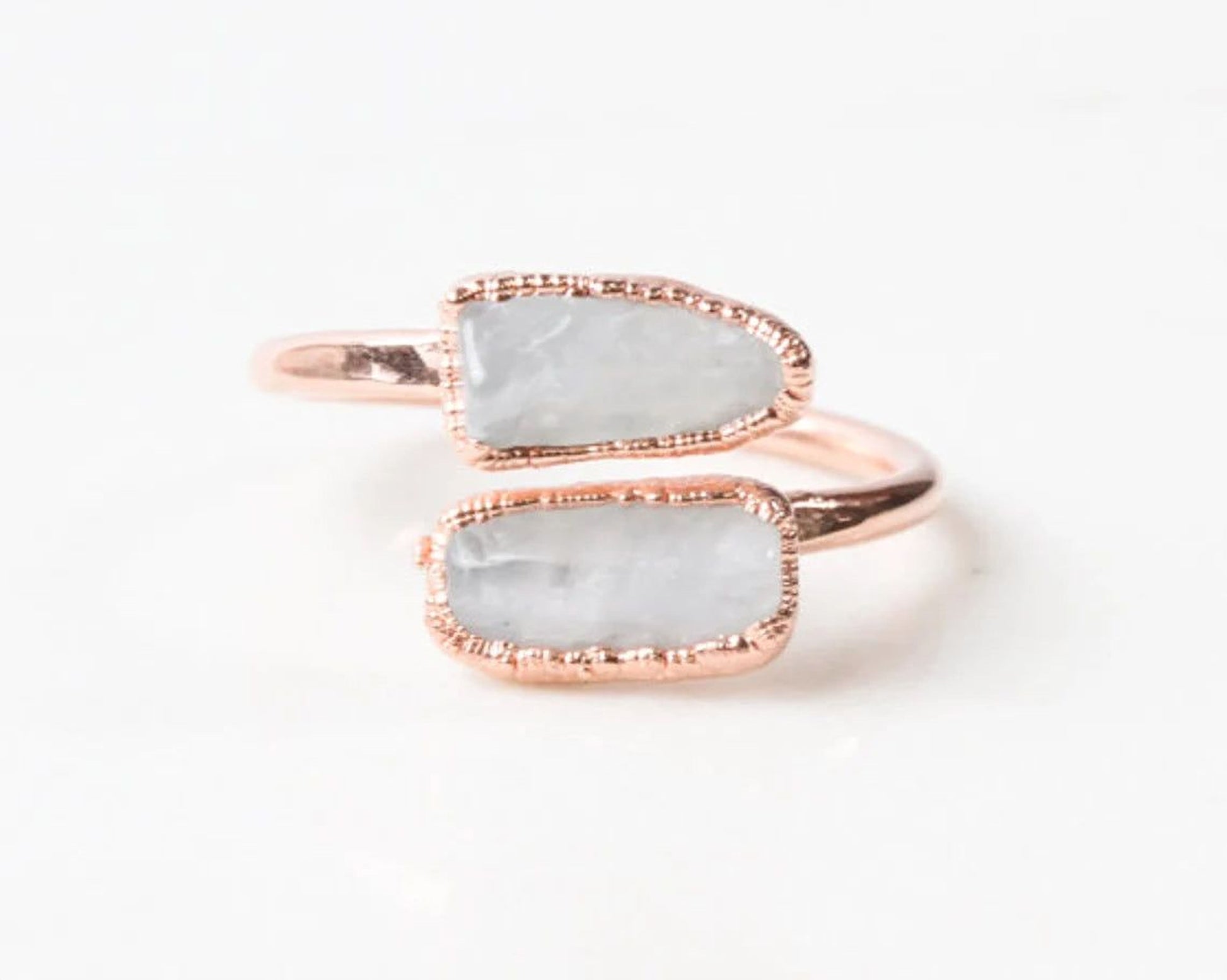 A ring with two large, white stones set in a rose gold band.