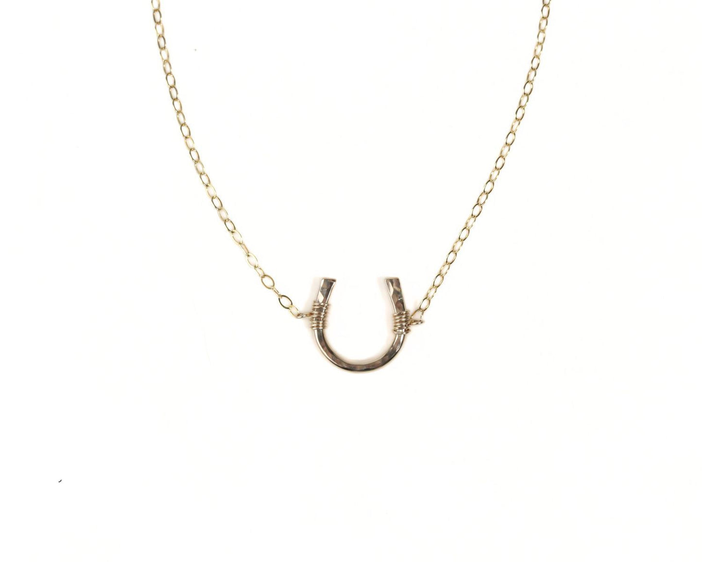 A gold-colored necklace with a horseshoe-shaped pendant.