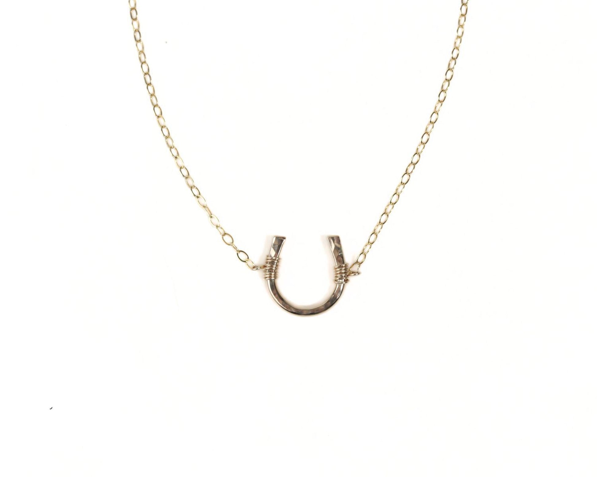 A gold-colored necklace with a horseshoe-shaped pendant.