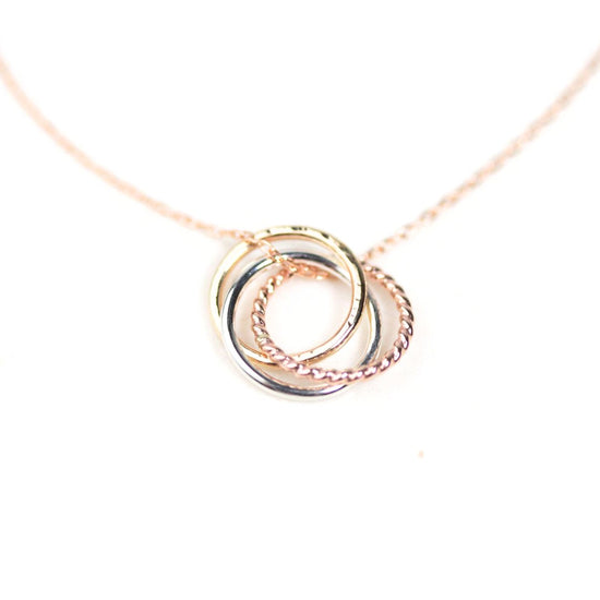 A delicate necklace with a pendant featuring three intertwined rings in a delicate, intricate design.