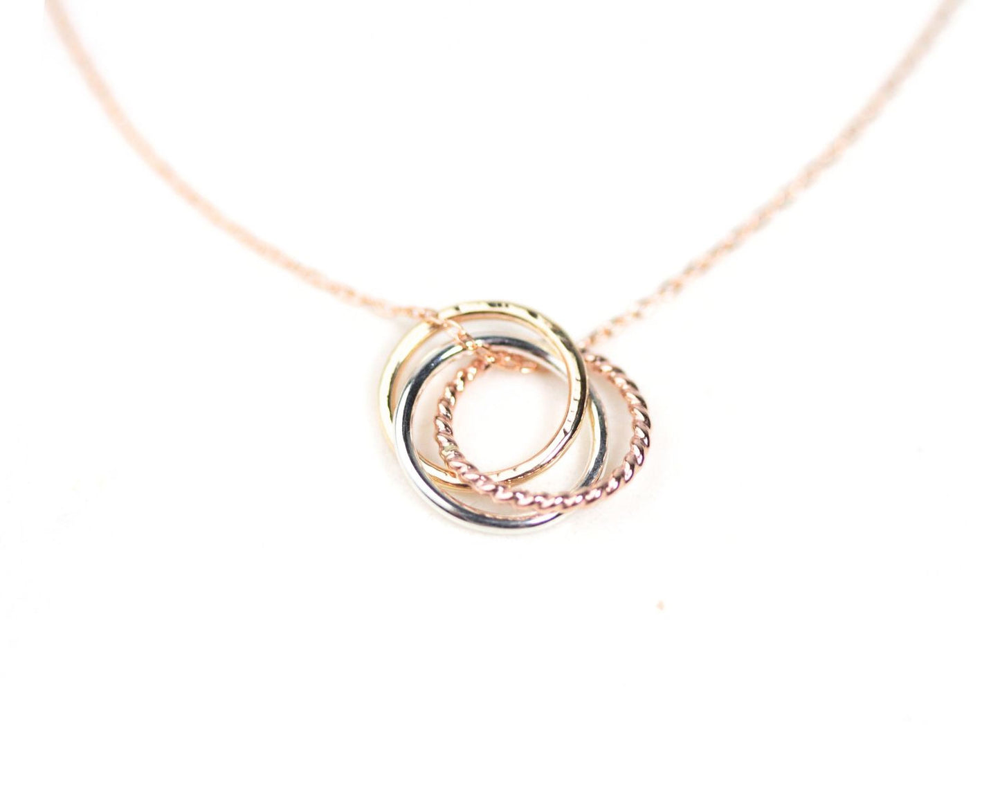 A delicate necklace with a pendant featuring three intertwined rings in a delicate, intricate design.