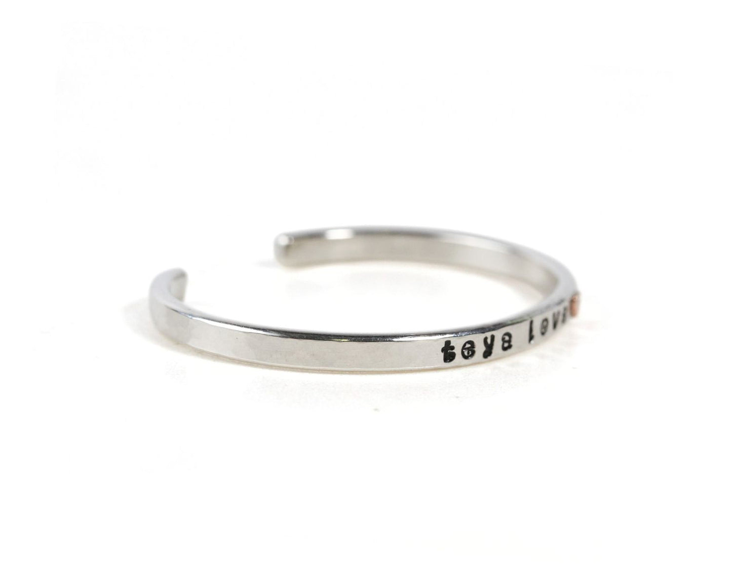 A silver bracelet with the text "Love" engraved on it.