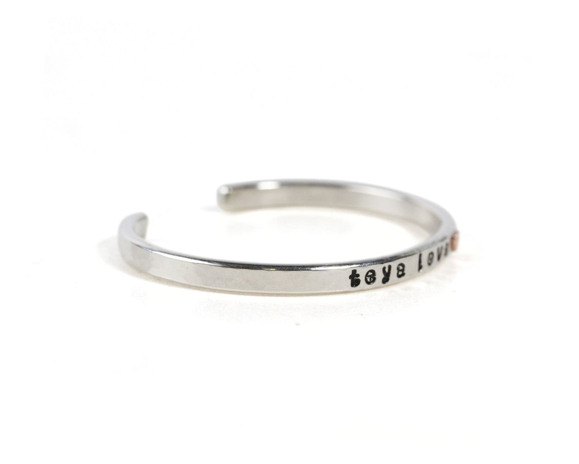 A silver bracelet with the text "Love" engraved on it.