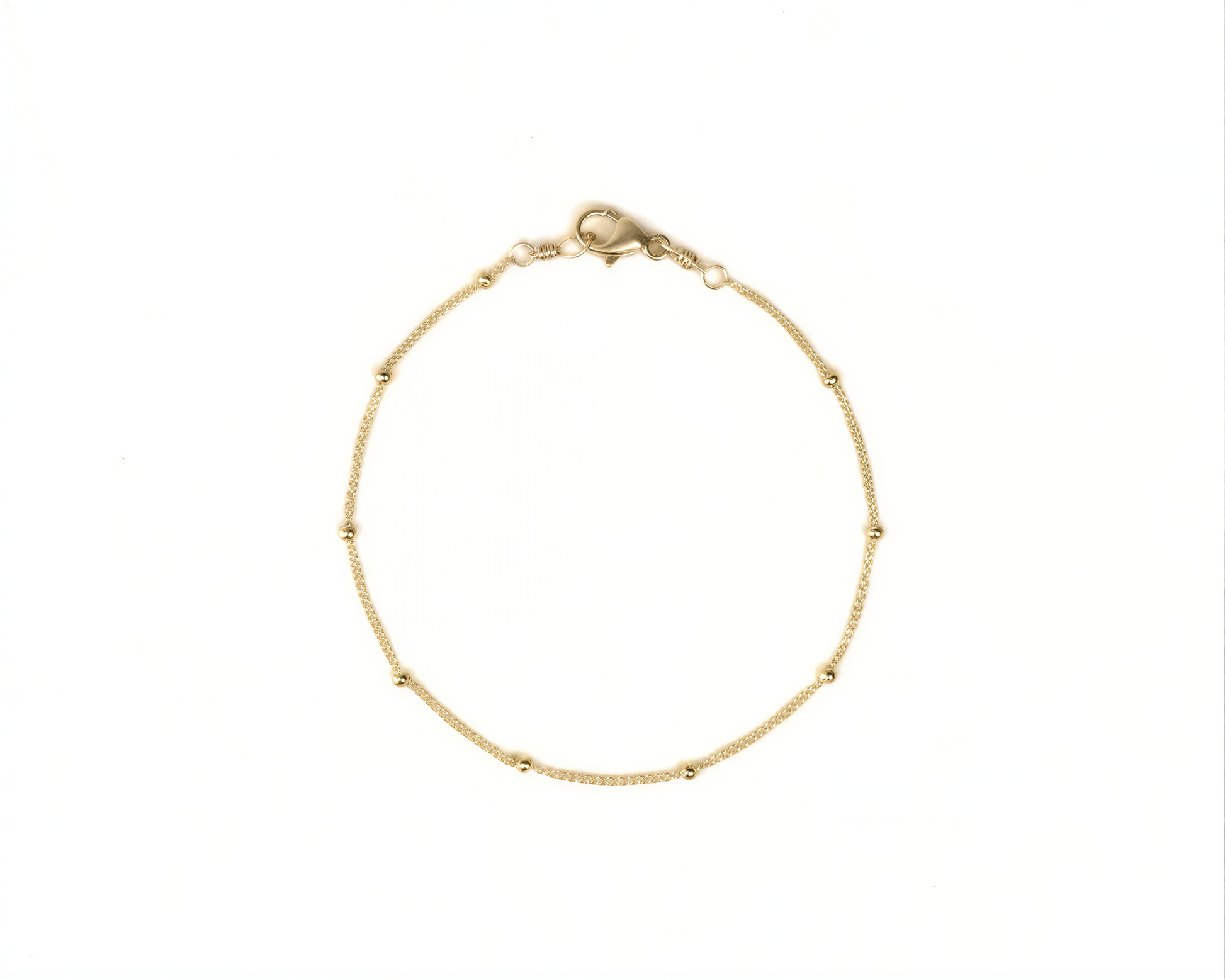 A delicate gold-colored bracelet with small beads on a white background.