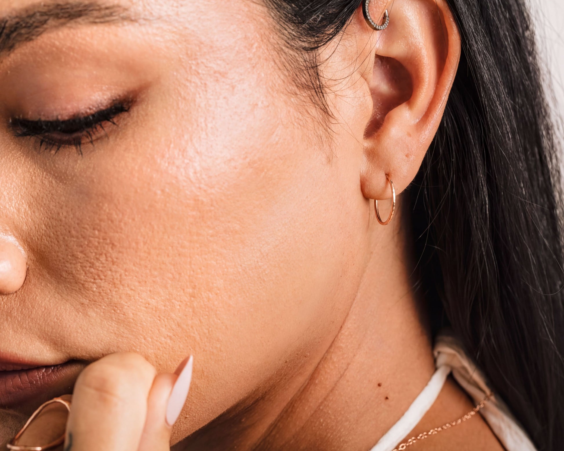 A close-up of a woman's face, focusing on her earrings and the side of her face.
