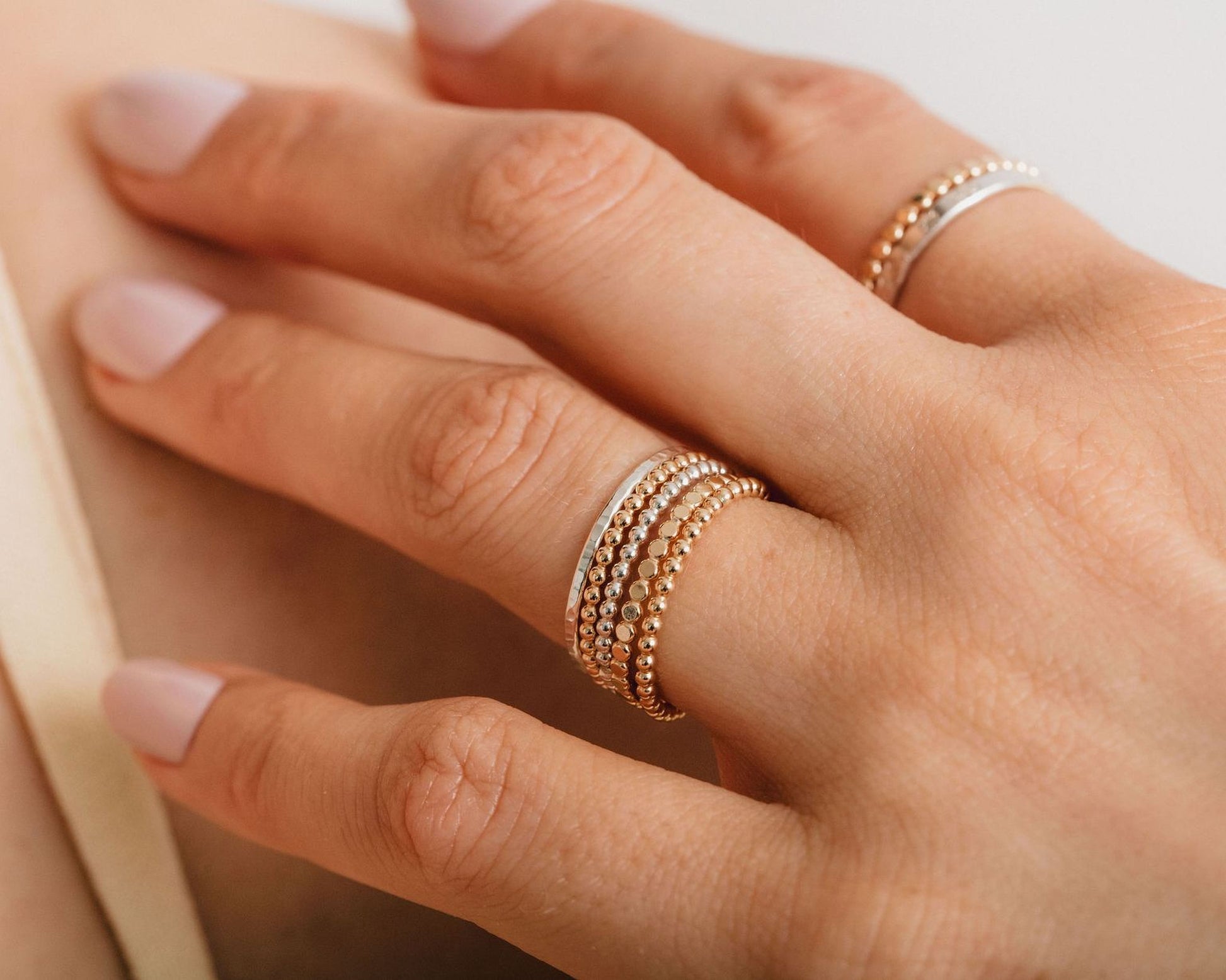 A close-up of a person's hand wearing multiple rings on the fingers.
