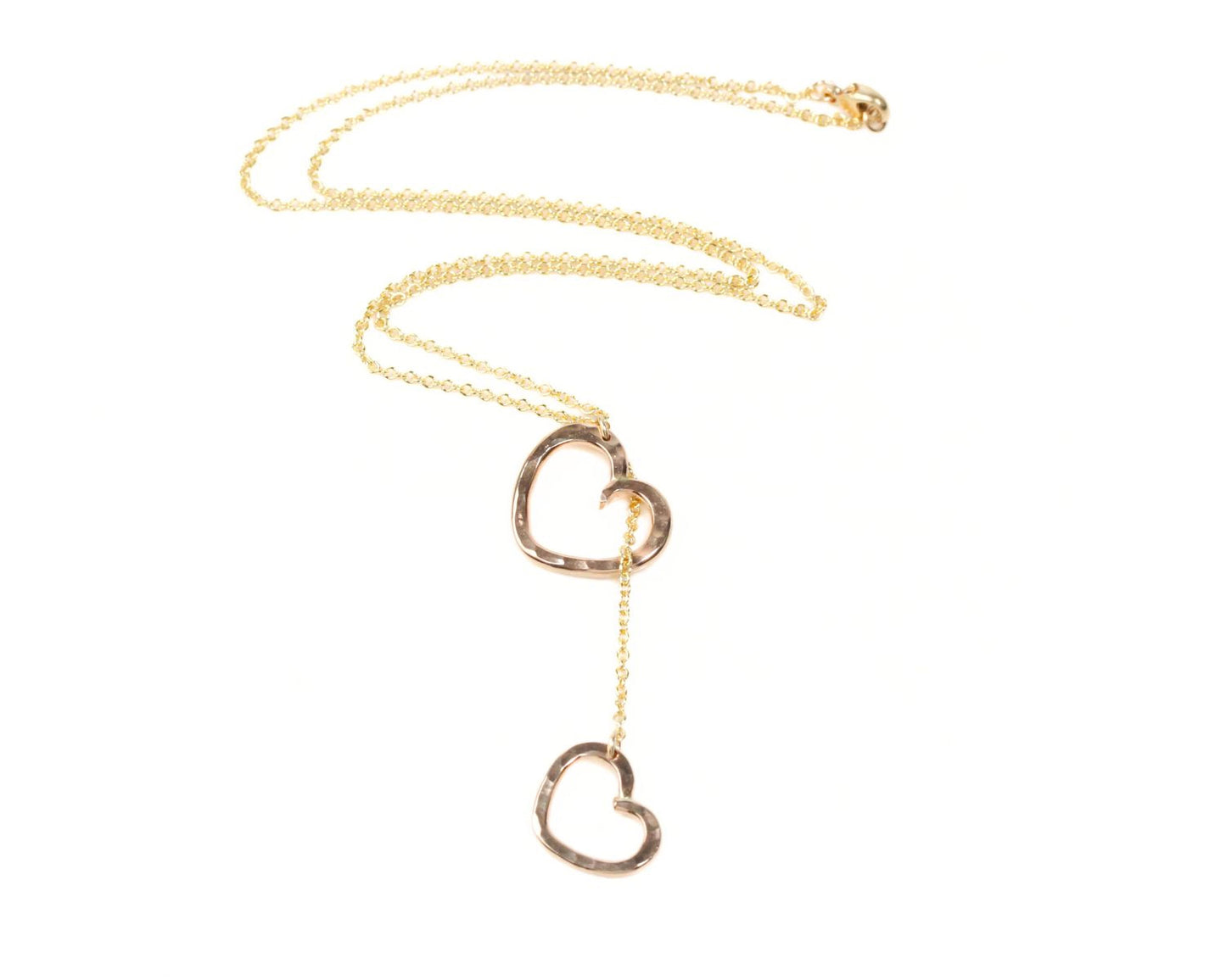A gold necklace with two heart-shaped pendants hanging from the chain.