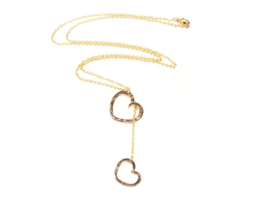A gold necklace with two heart-shaped pendants hanging from the chain.