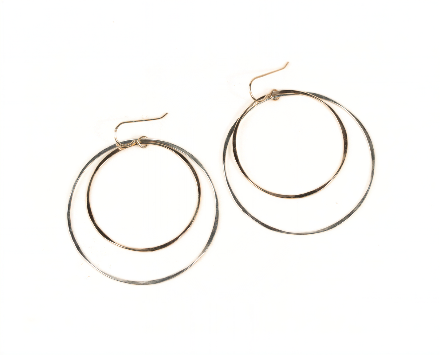 A pair of gold-toned hoop earrings with a layered design, featuring two concentric circles.