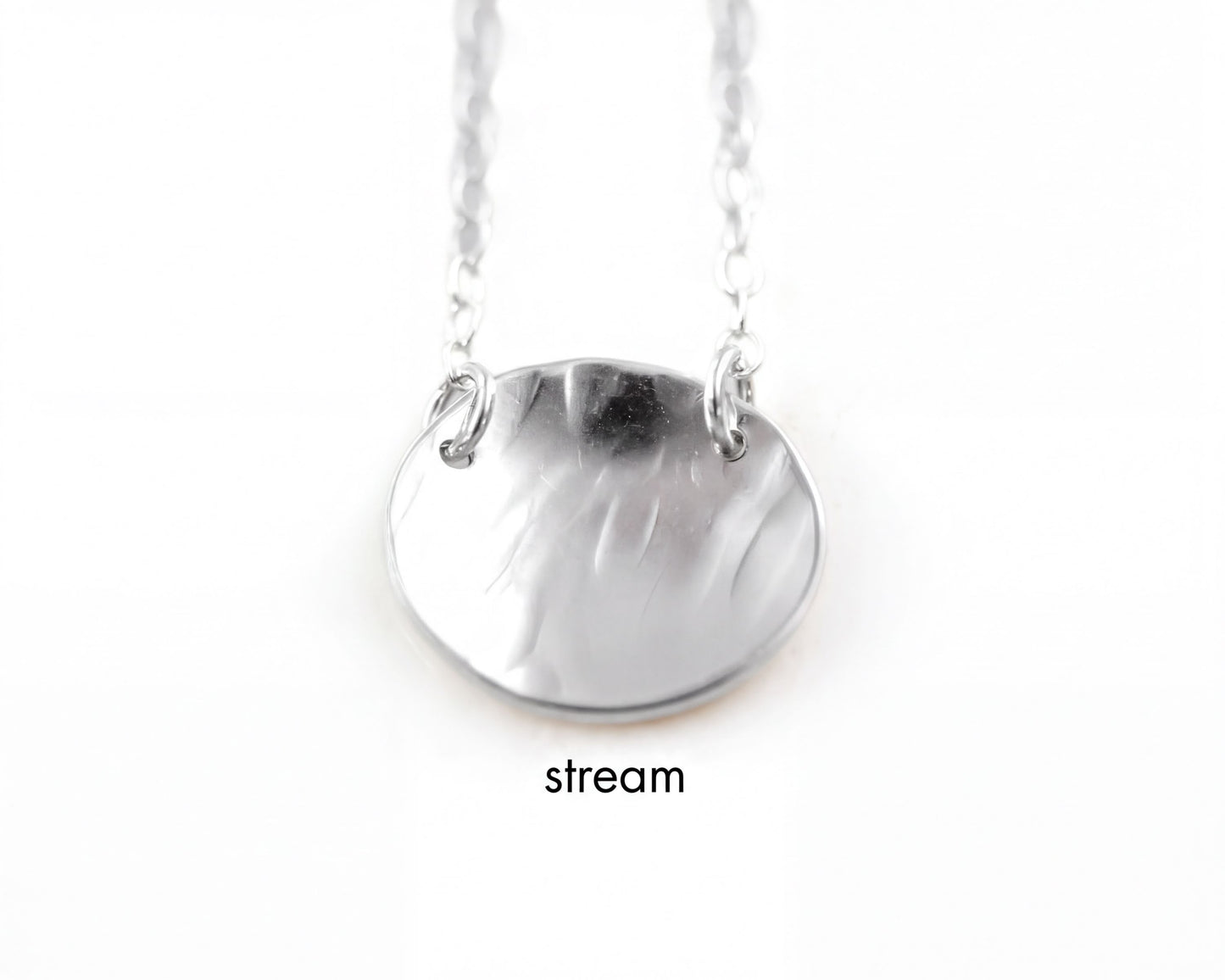 A silver necklace with a round pendant, suspended from a chain.