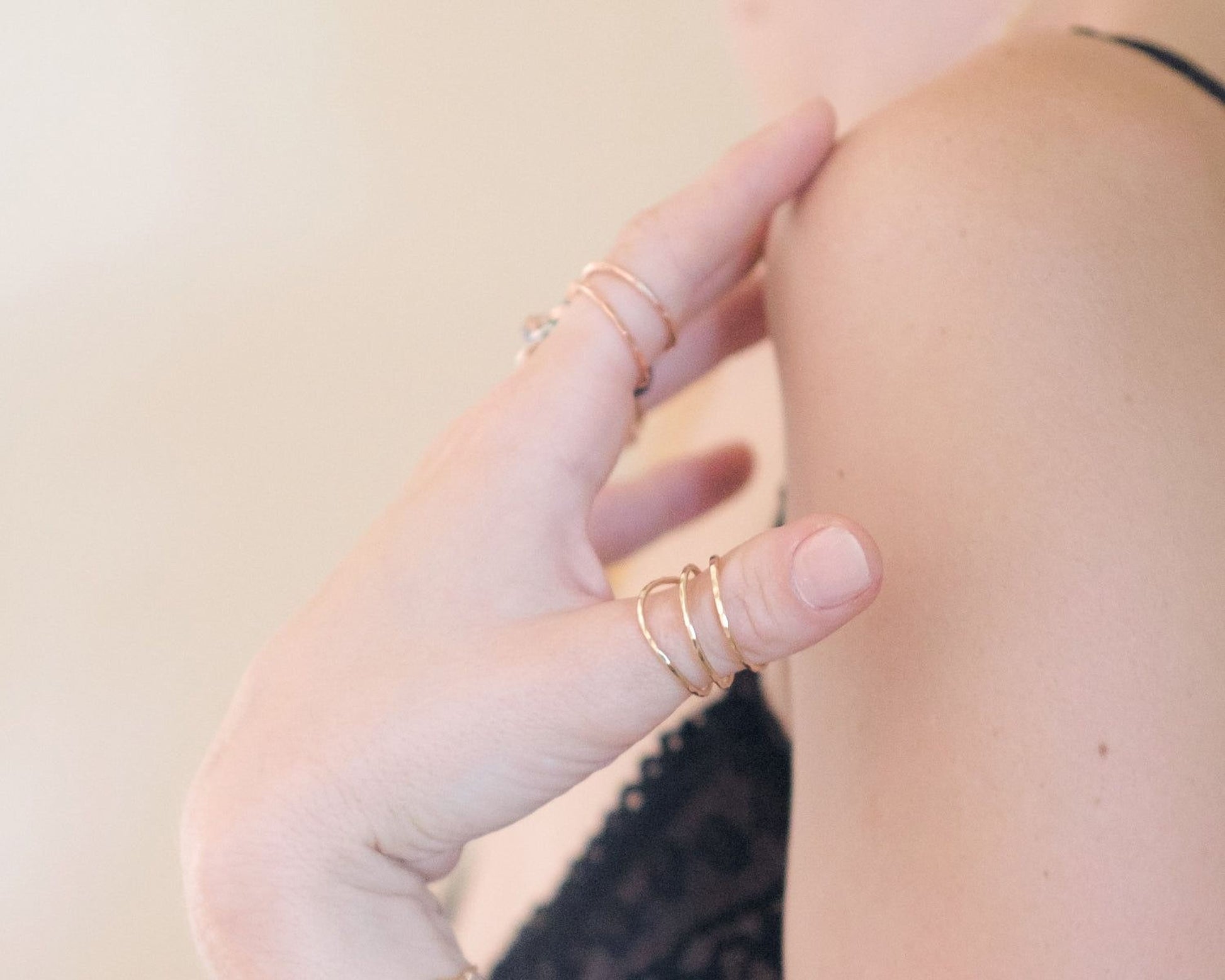 A close-up of a person's hand wearing multiple rings on their fingers.