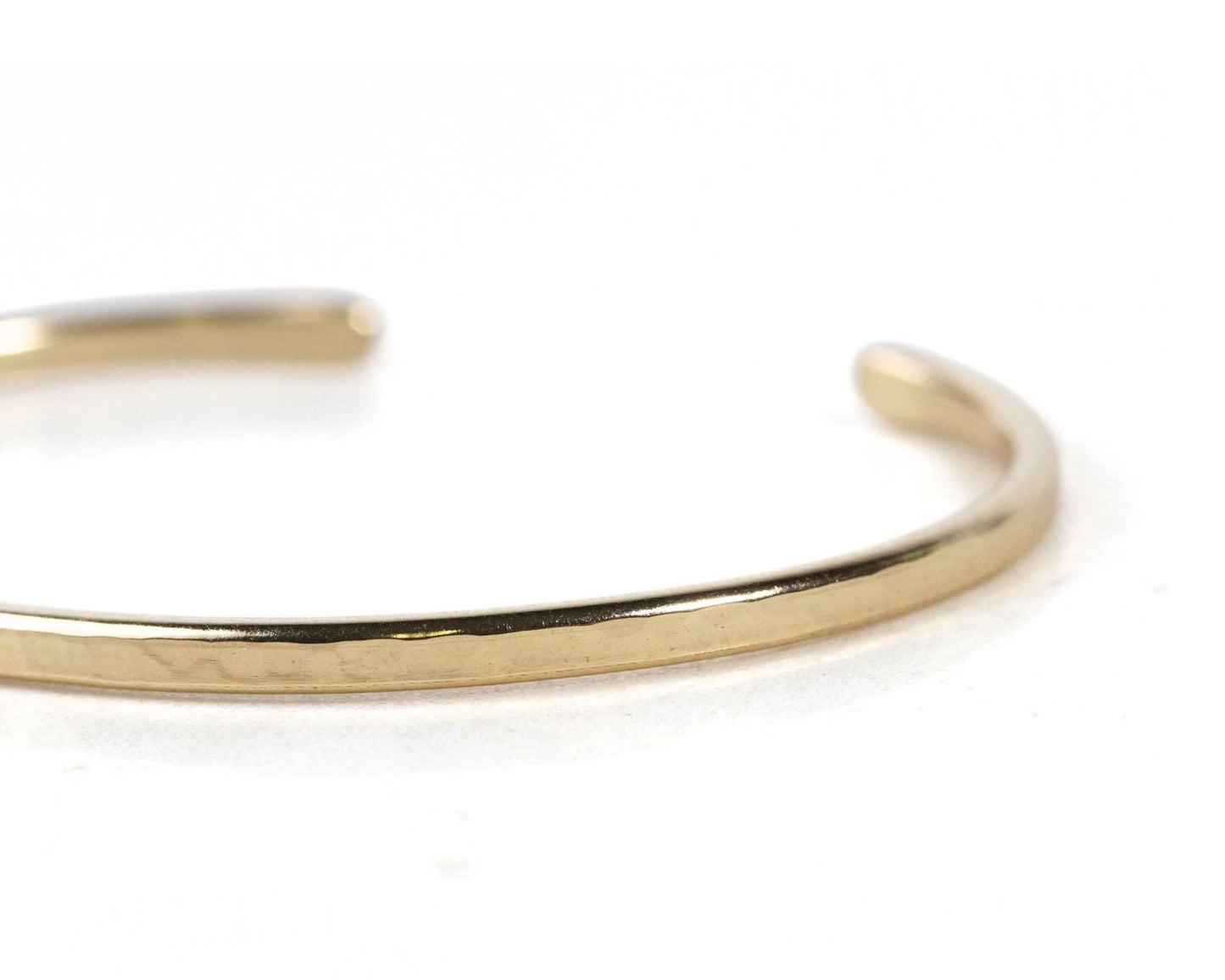 A close-up view of a gold-colored bracelet or cuff on a white background.
