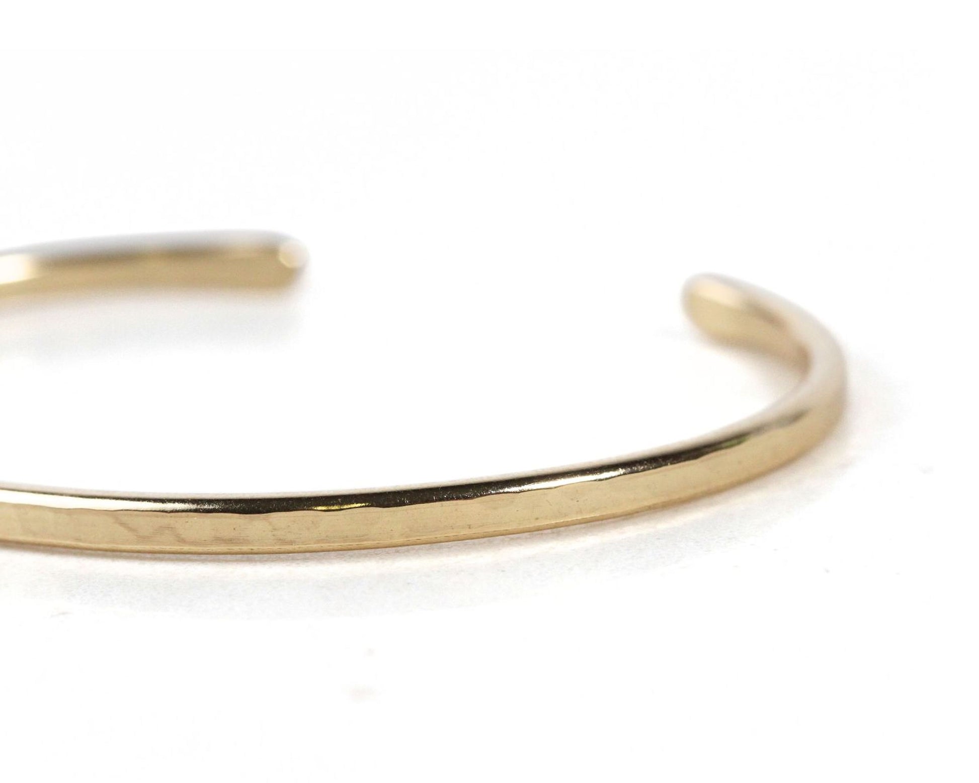 A close-up view of a gold-colored bracelet or cuff on a white background.