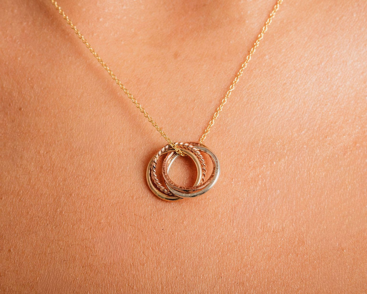 A close-up view of a gold necklace with a pendant featuring a series of rings.