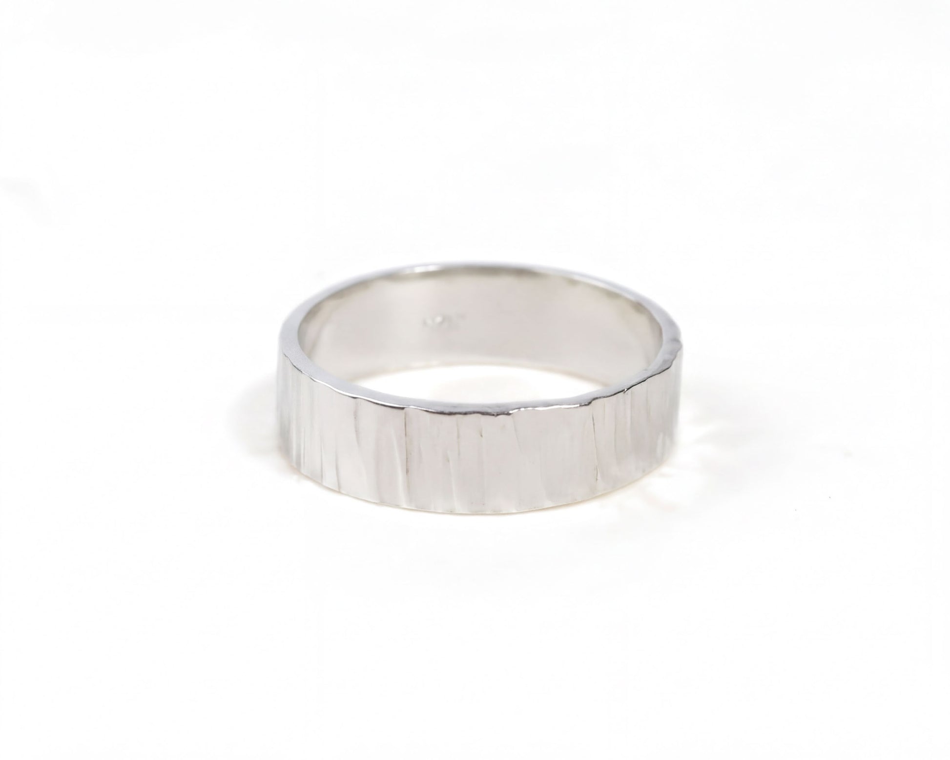 A silver ring with a textured band is shown against a white background.