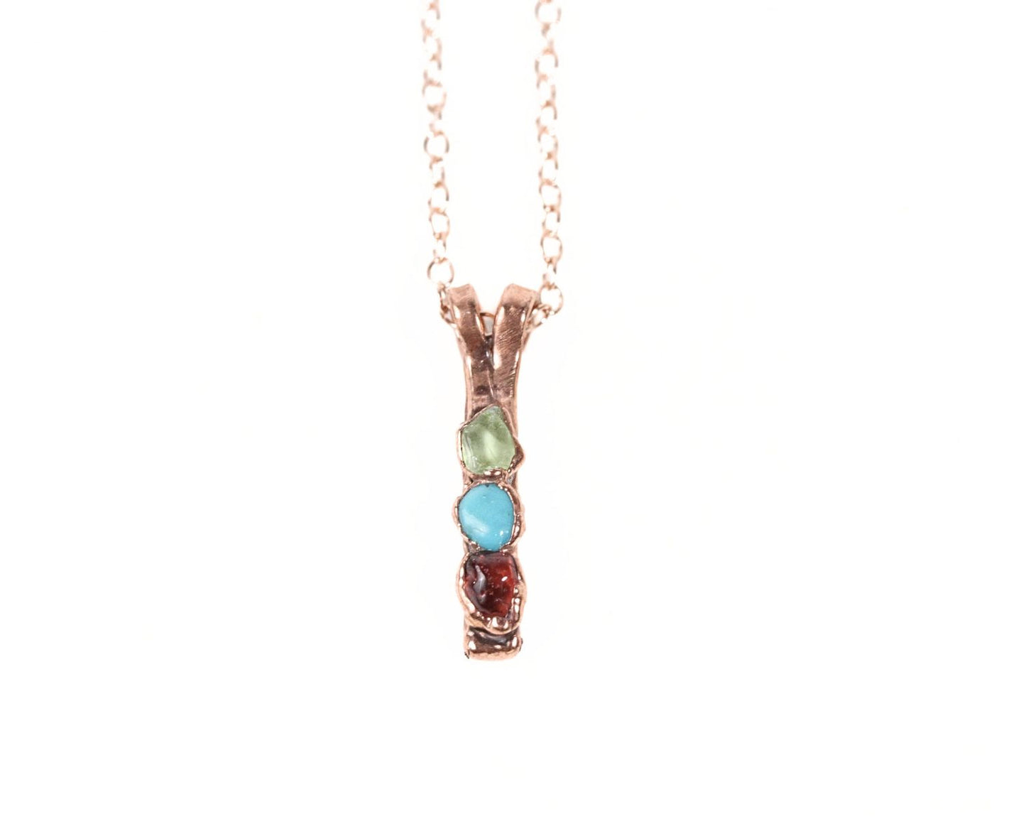 A necklace with a pendant featuring three colored gemstones.