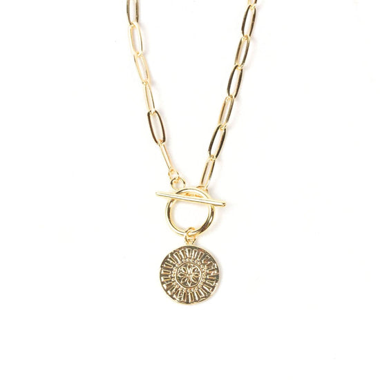 A gold-colored necklace with a round pendant featuring a sun-like design.