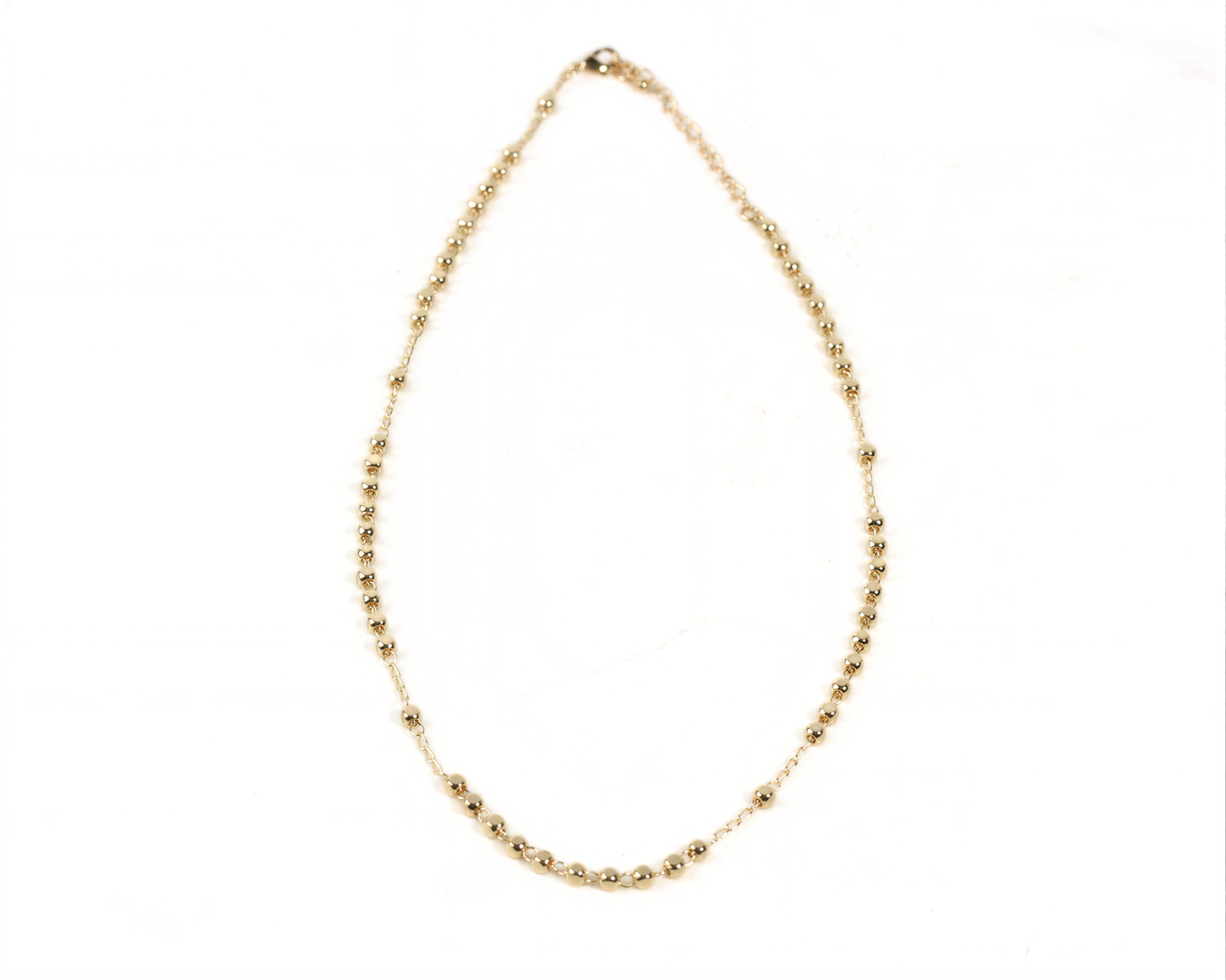 A gold-colored necklace with small beads or stones attached to it.