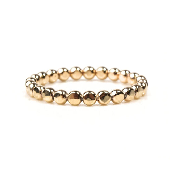 A gold-colored bracelet made of small, shiny beads arranged in a circular pattern.