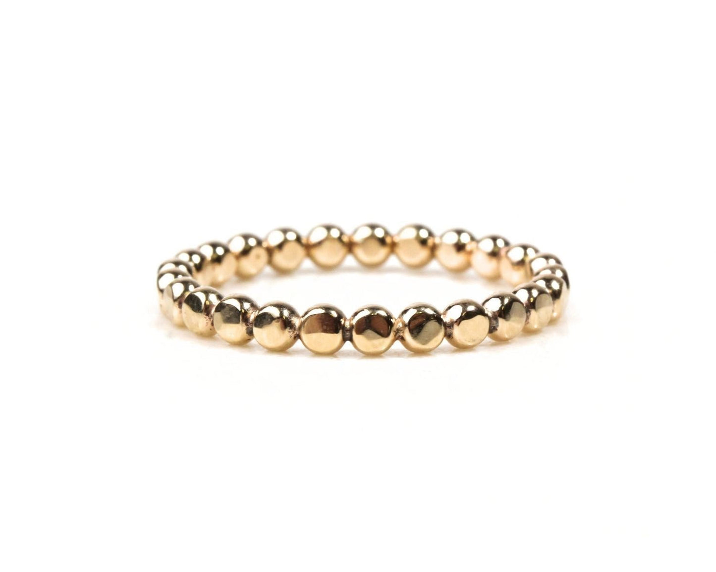 A gold-colored bracelet made of small, shiny beads arranged in a circular pattern.