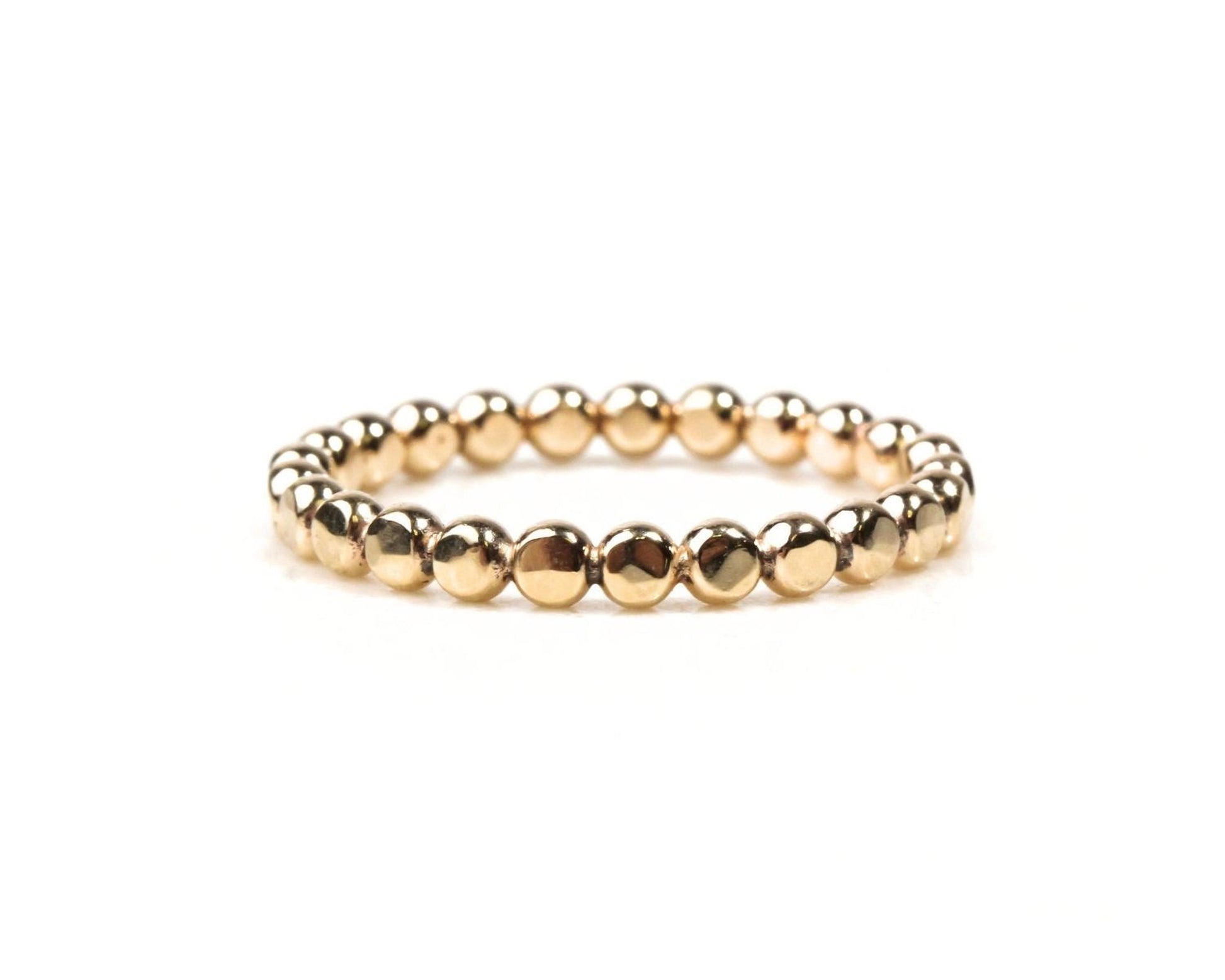 A gold-colored bracelet made of small, shiny beads arranged in a circular pattern.