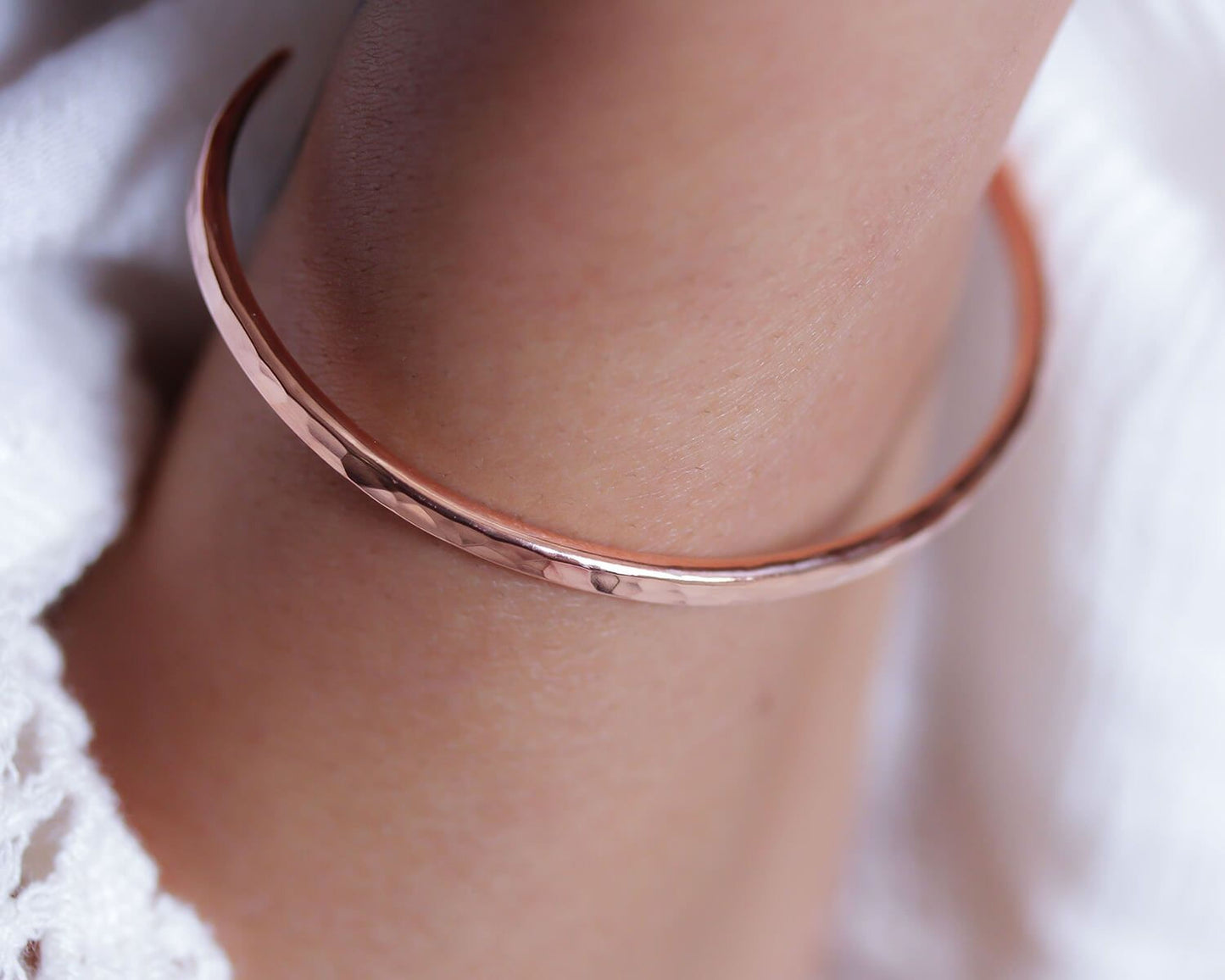 A close-up image of a person's arm wearing a copper-colored bracelet.