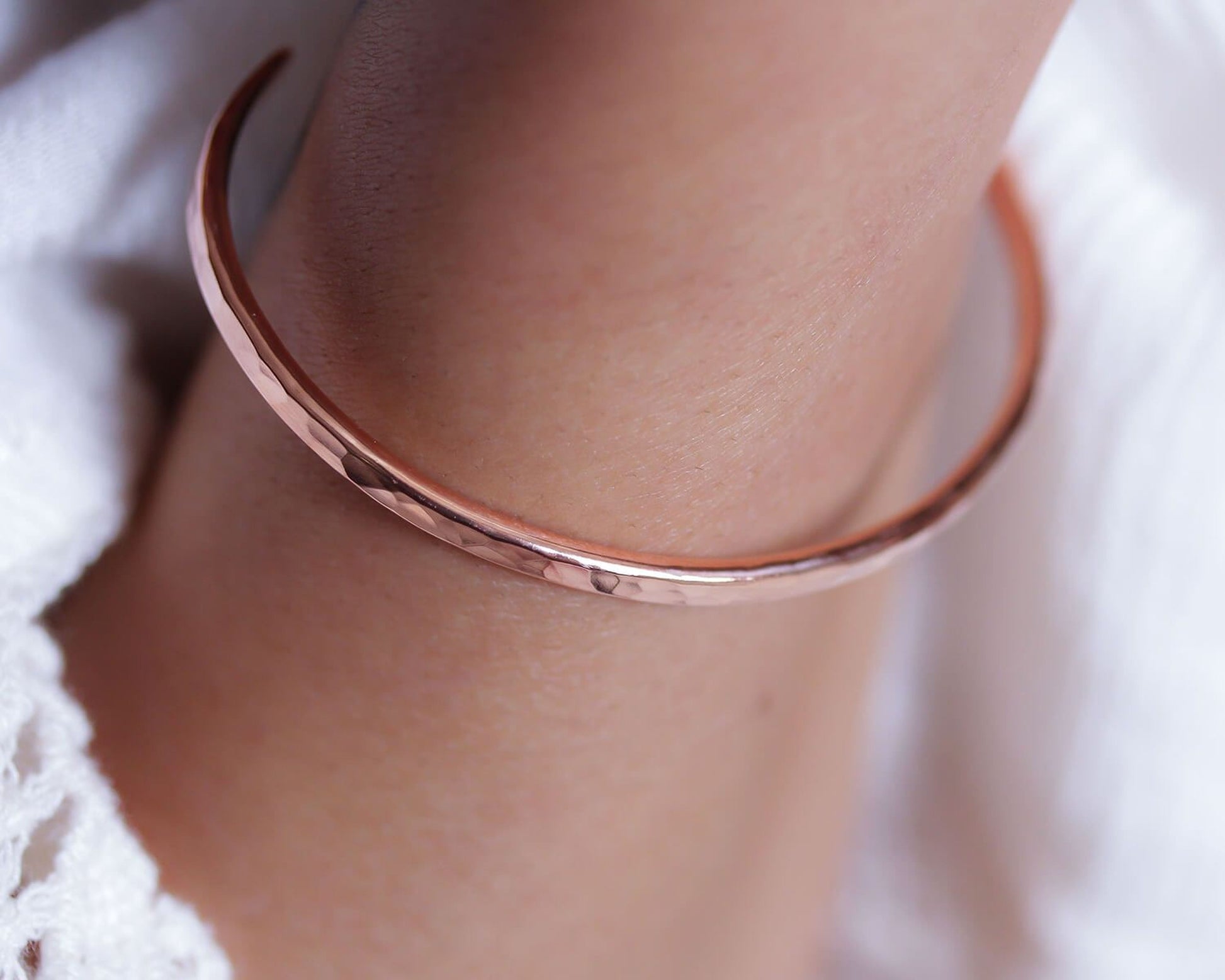 A close-up image of a person's arm wearing a copper-colored bracelet.