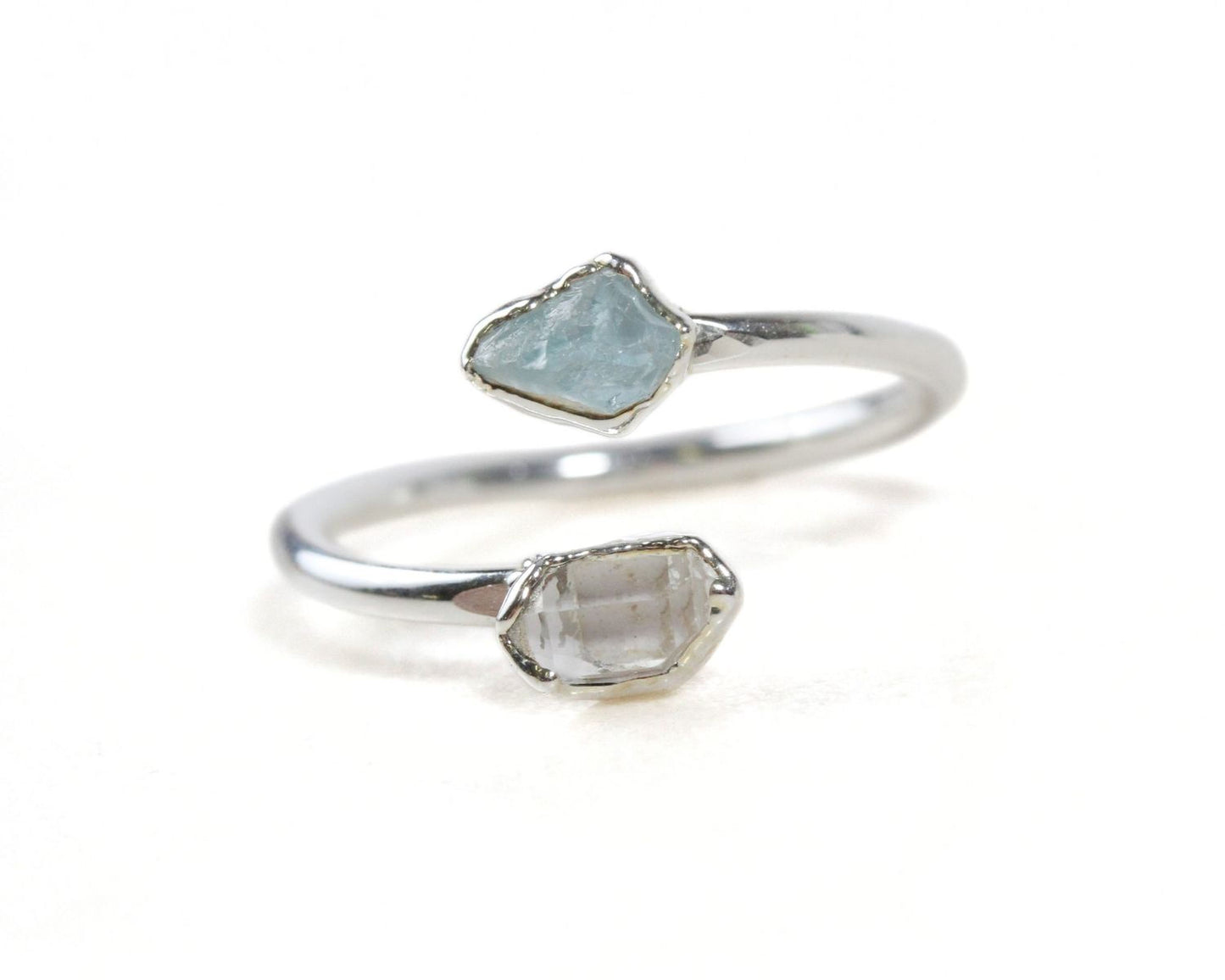 A silver ring with two gemstone stones, one blue and one clear, set in a twisted design.