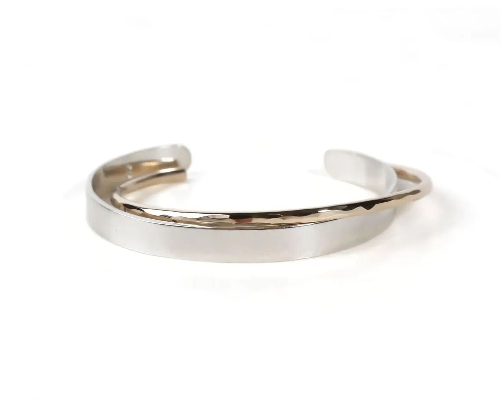A silver-colored bracelet with a textured design, featuring a curved shape and a metallic finish.