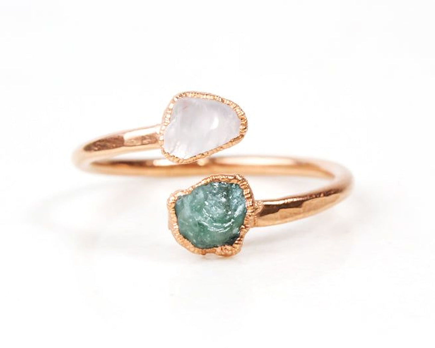 A gold ring with two gemstones, one white and one green, set in the center.
