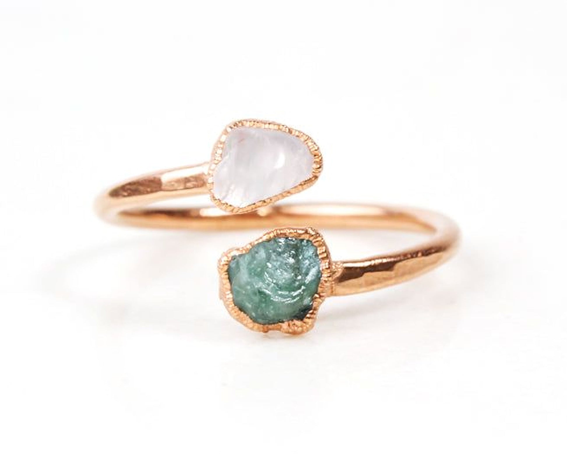 A gold ring with two gemstones, one white and one green, set in the center.