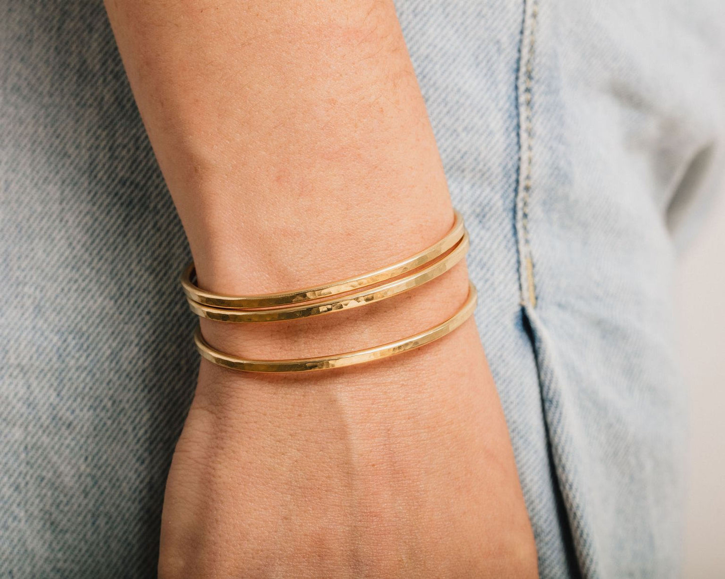 A close-up view of a person's wrist wearing a gold-colored bracelet.