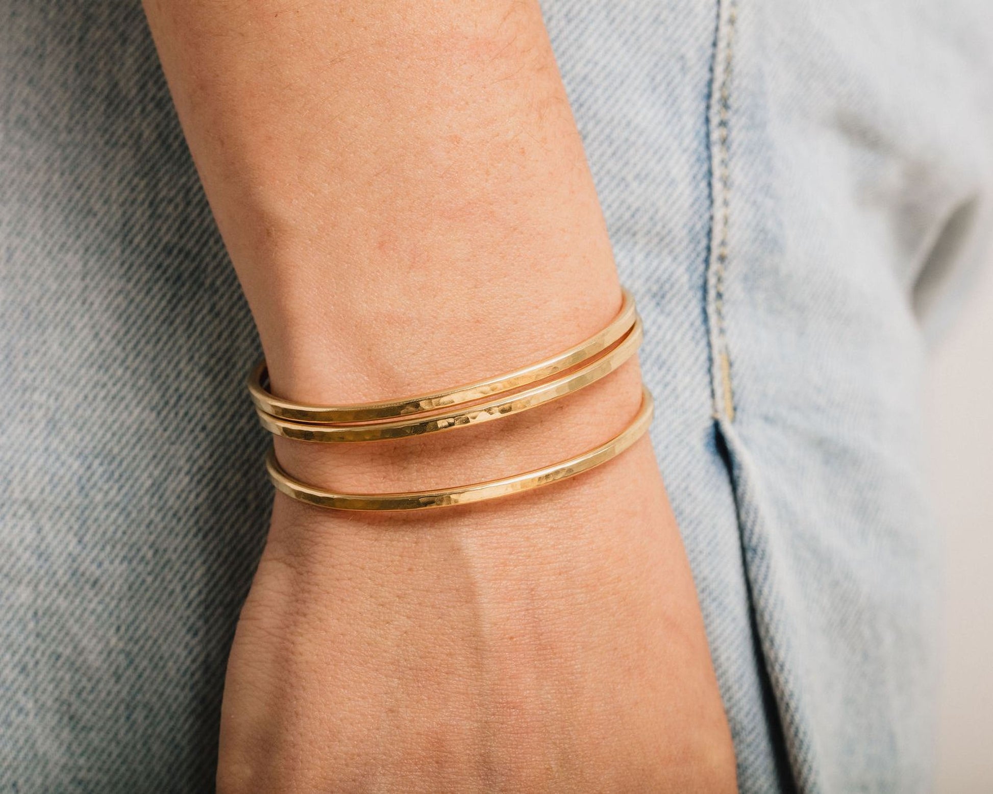 A close-up view of a person's wrist wearing a gold-colored bracelet.
