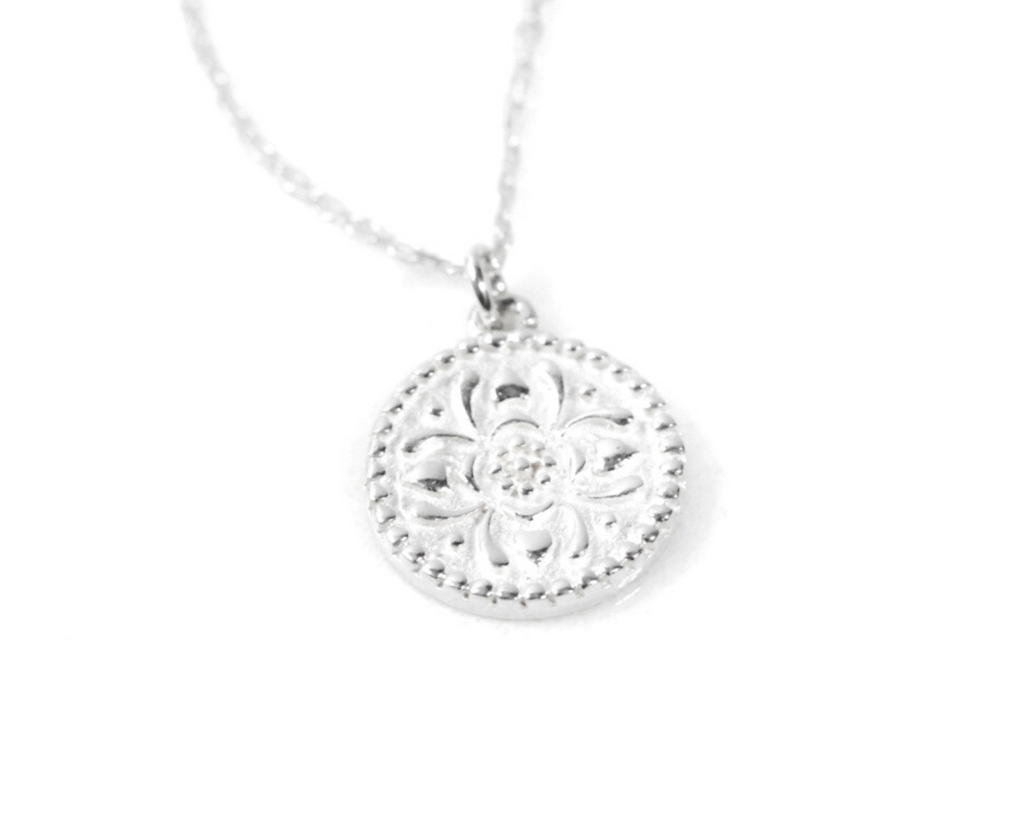 An artistic floral motif gleams from the 1/2 inch Silver coin pendant. Dots, hearts, and arching petal shapes radiate outward. This silver flower necklace is handcrafted entirely in 925 Sterling Silver, complete with our 1.1mm Sterling Silver chain.