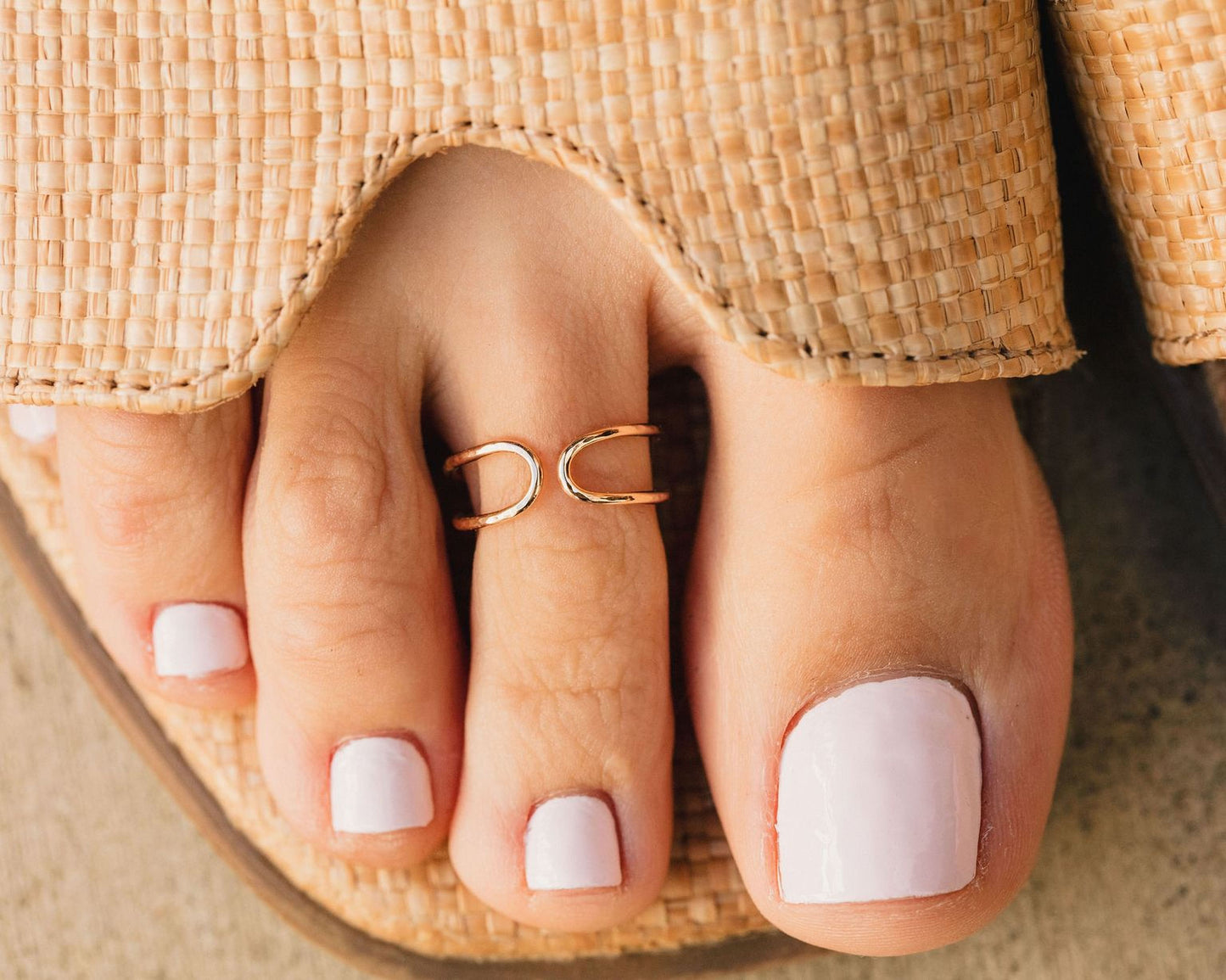 A close-up view of a person's foot wearing a ring on the toe and having painted toenails.