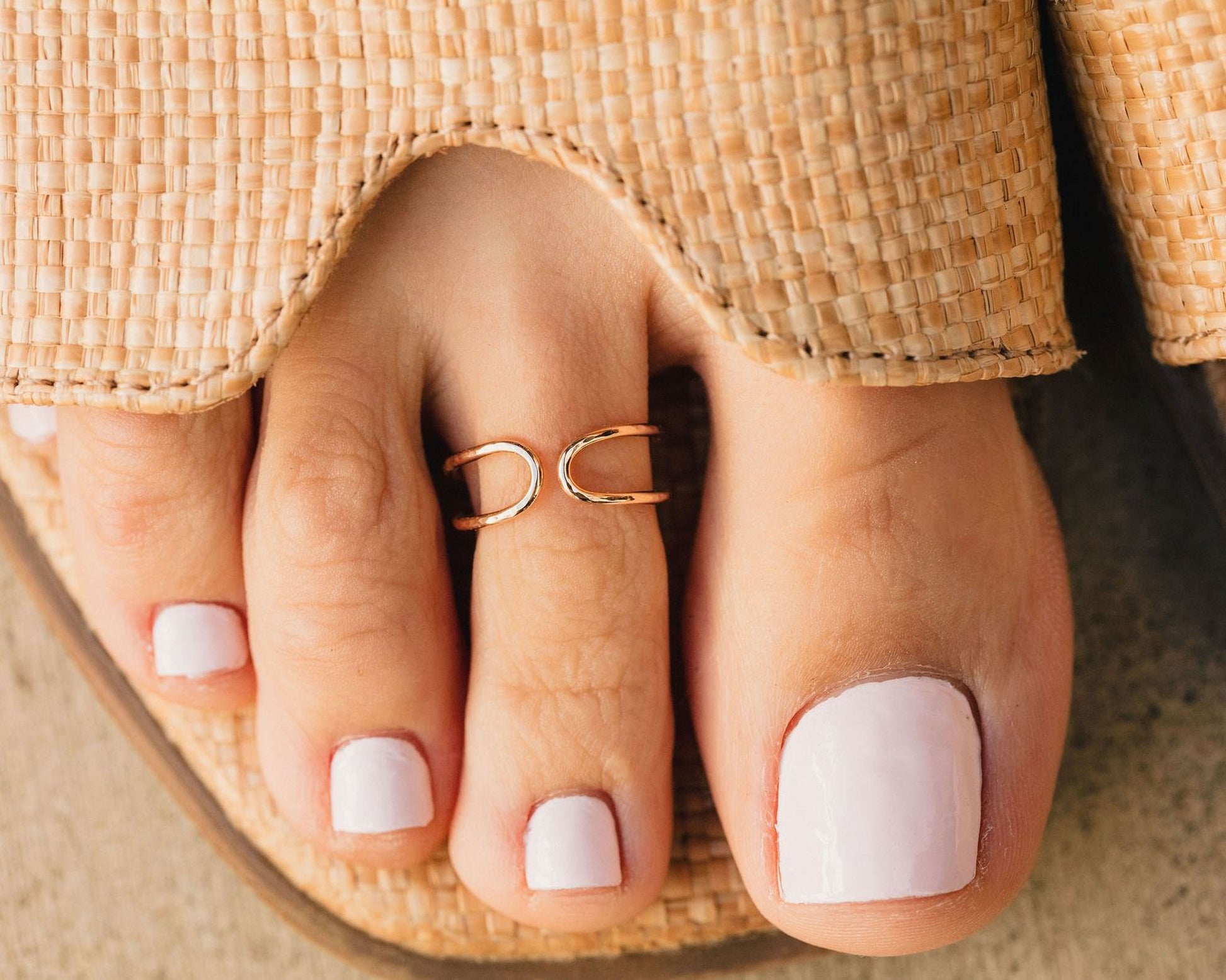 A close-up view of a person's foot wearing a ring on the toe and having painted toenails.