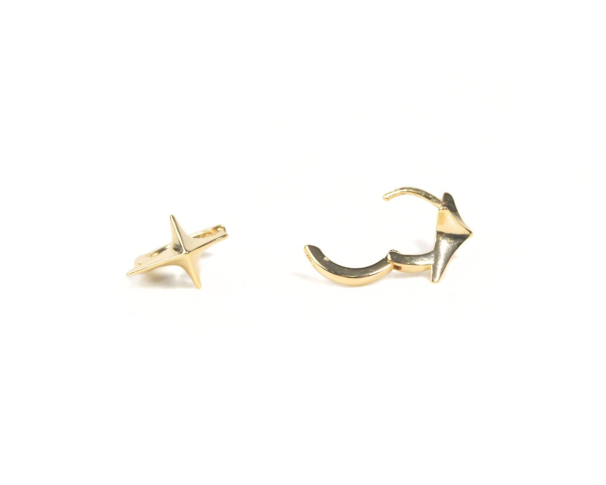 two gold-colored earrings, one with a star-shaped design and the other with a curved shape, both sitting on a white background.