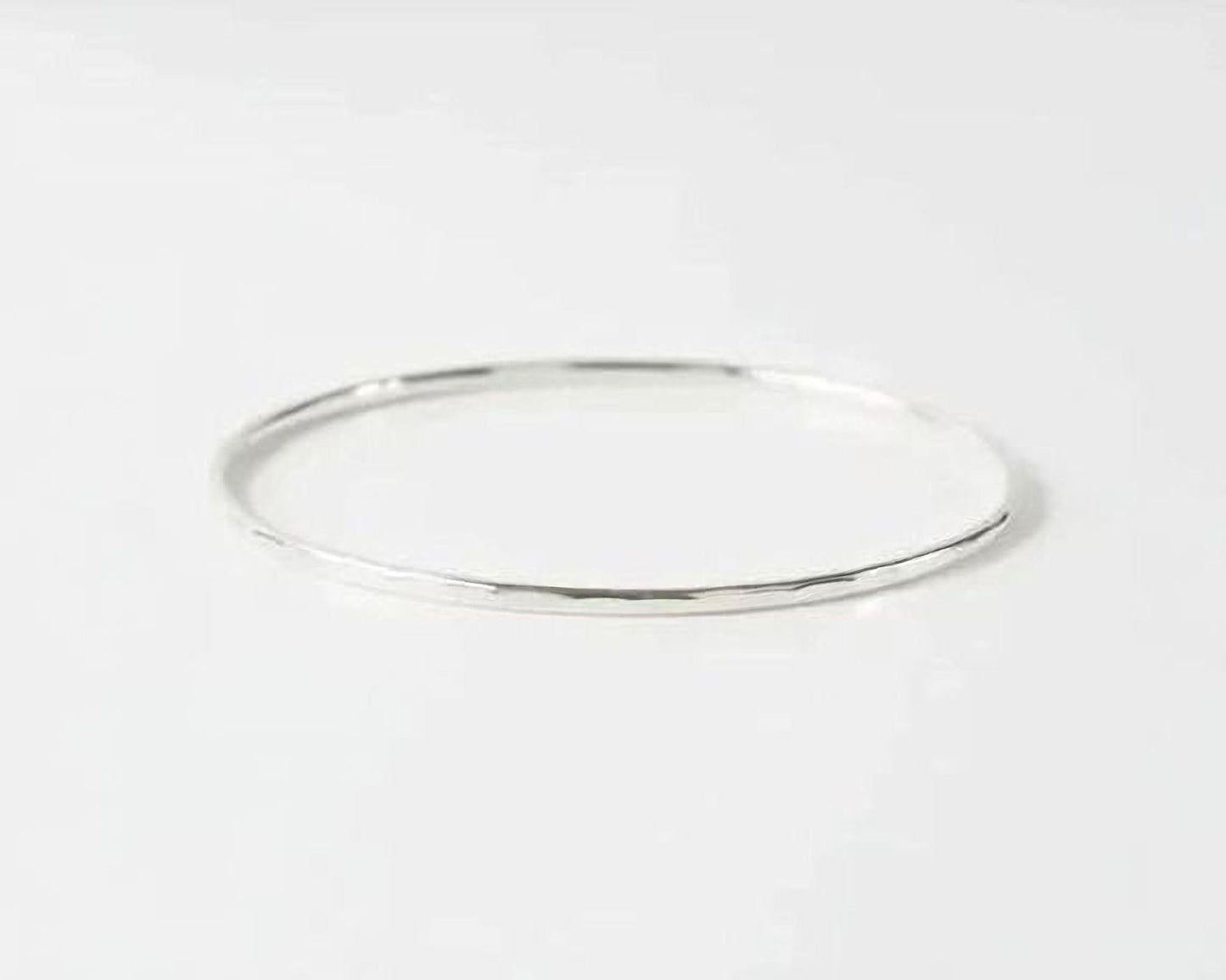 A simple silver bangle bracelet is shown against a plain white background.