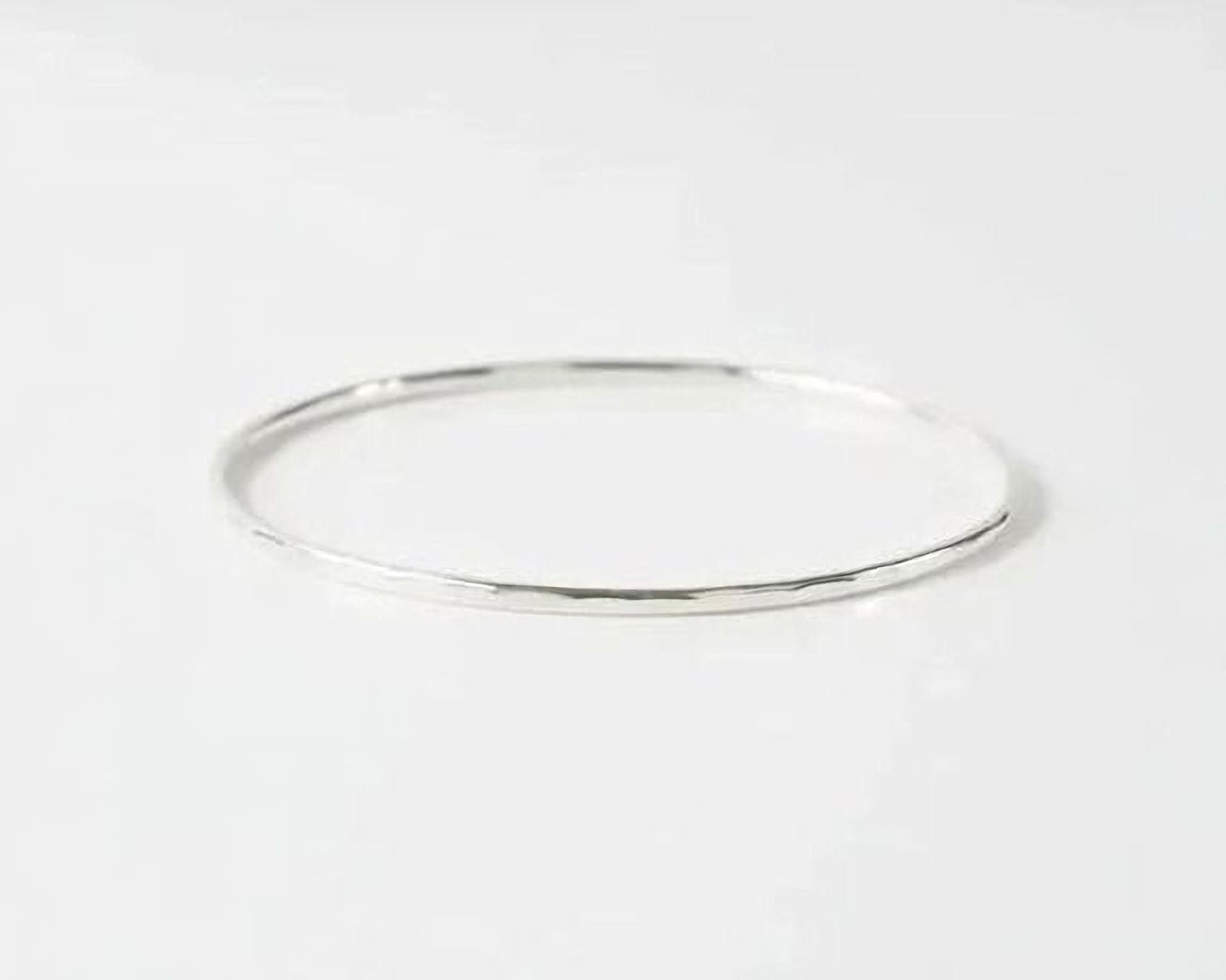 A simple silver bangle bracelet is shown against a plain white background.
