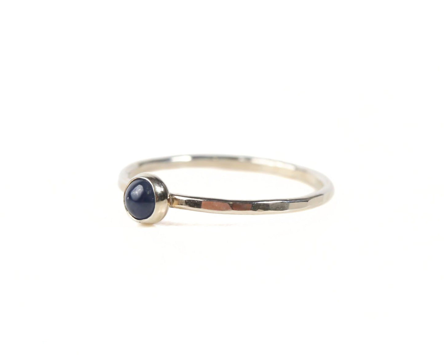 A simple silver ring with a blue gemstone, possibly a sapphire, set in the center.