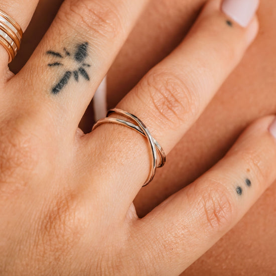 A close-up of a person's hand wearing a ring and having a tattoo on one of the fingers.