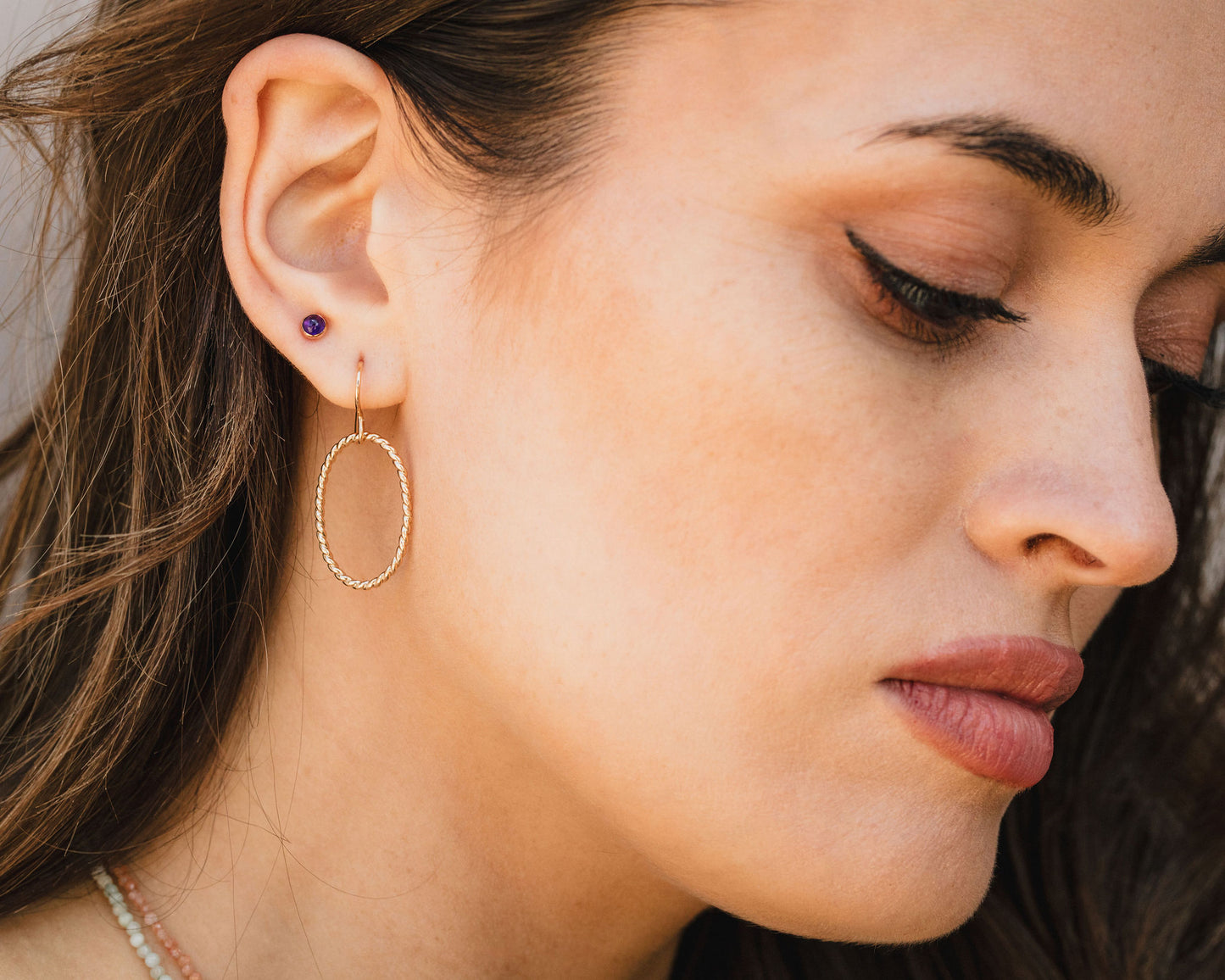 A close-up of a woman's face, focusing on her earrings and lips.